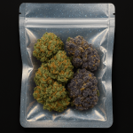 A high-resolution image of a sealed holographic Mylar bag filled with dense, trichome-covered cannabis buds in green and purple hues, displayed against a black background.